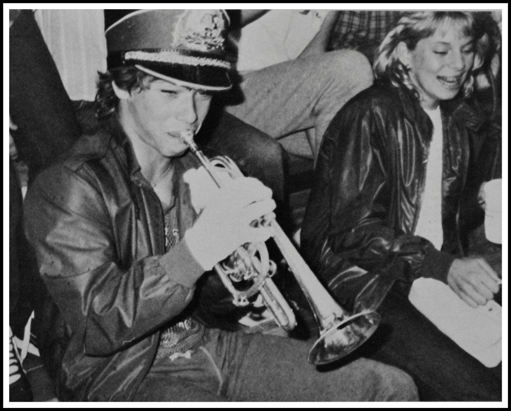 Dude in the Bleachers Playing Trumpet